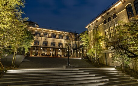 A building with multiple floors, a staircase leading to the entrance, and surrounding trees.