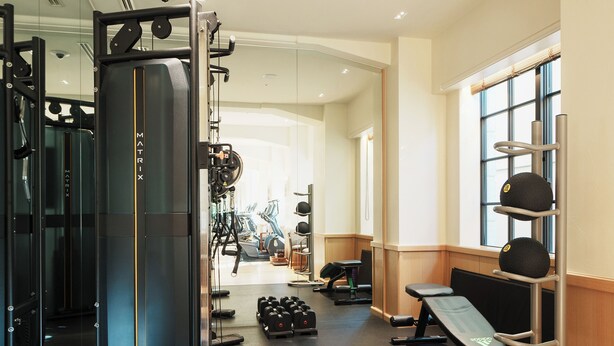 Un gimnasio con equipo de ejercicio, cintas de correr y mancuernas.