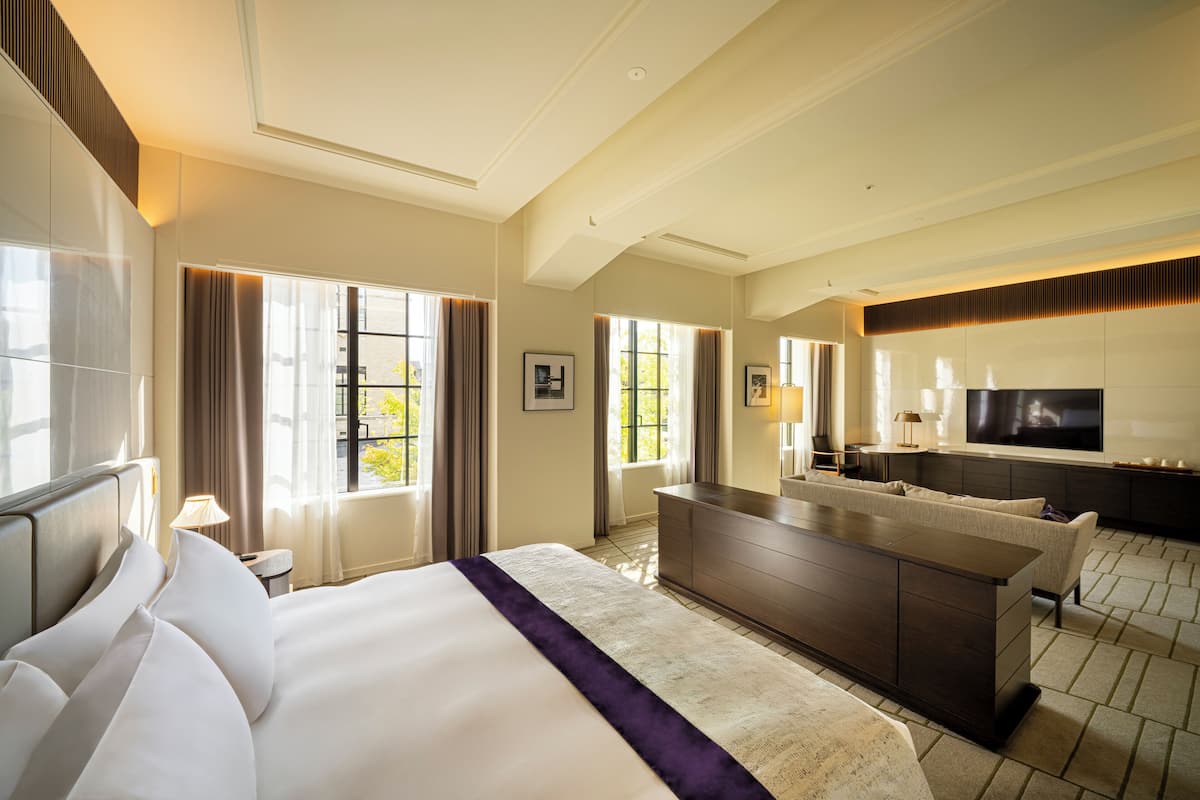 Ein Hotelzimmer mit einem großen Bett, einem Schreibtisch, einem Fernseher und Blick ins Freie.