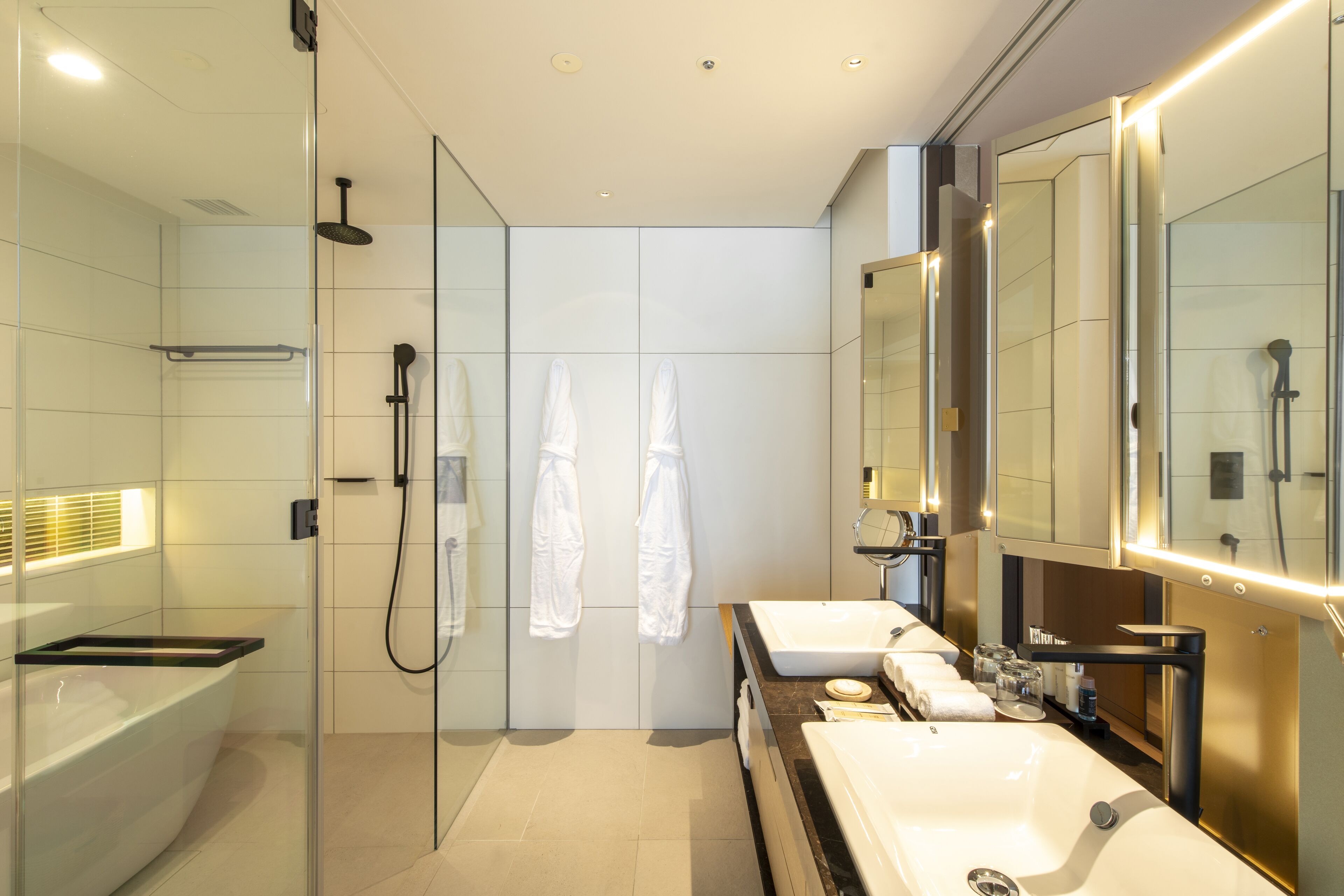 A modern bathroom with a glass-enclosed shower, two sinks, and a large mirror.