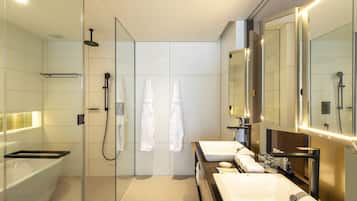 A modern bathroom with a glass-enclosed shower, two sinks, and a large mirror.