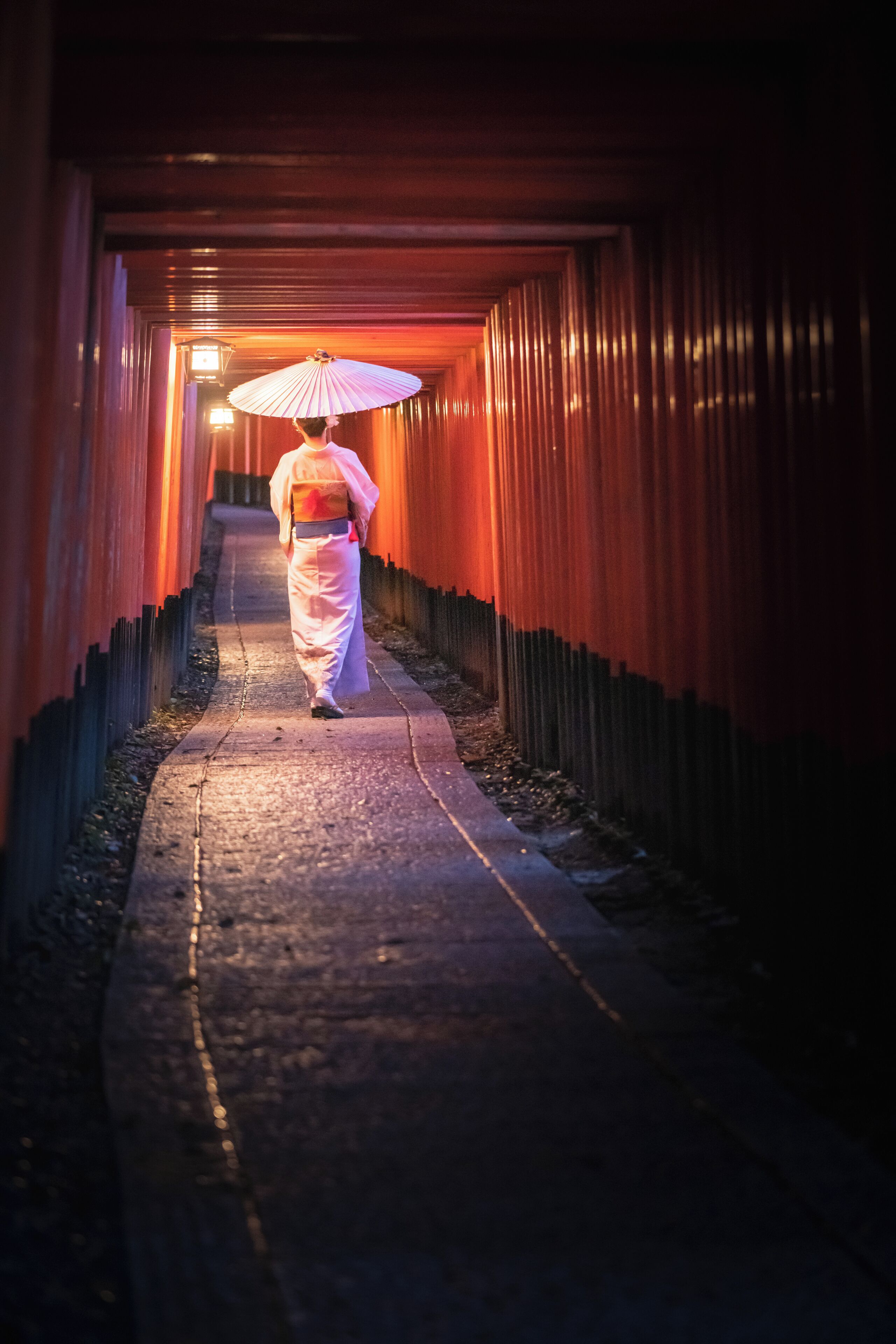 Un pasillo con una persona caminando bajo un paraguas iluminado.
