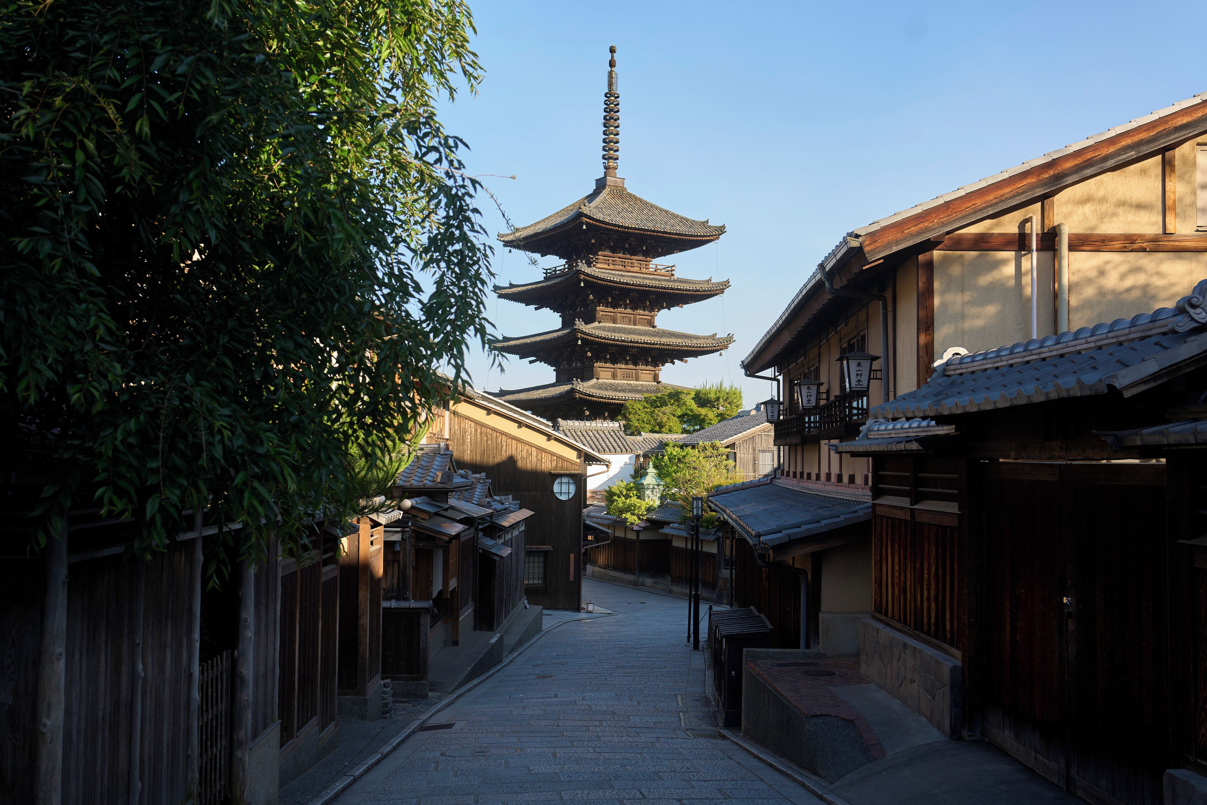 A traditional Japanese street with a multi-tiered pagoda in the background.