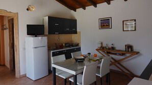 A compact kitchen with a refrigerator, stove, and dining area with chairs and a table. - "Pride and Prejudice" - Residences Gattopardu (castiadas)
