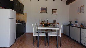 A kitchen with a white refrigerator, black cabinets, a dining table with four chairs, and a wooden ceiling. - "Pride and Prejudice" - Residences Gattopardu (castiadas)