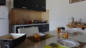 A modern kitchen with black cabinets, a tiled backsplash, and a dining area with a glass table. - "Pride and Prejudice" - Residences Gattopardu (castiadas)