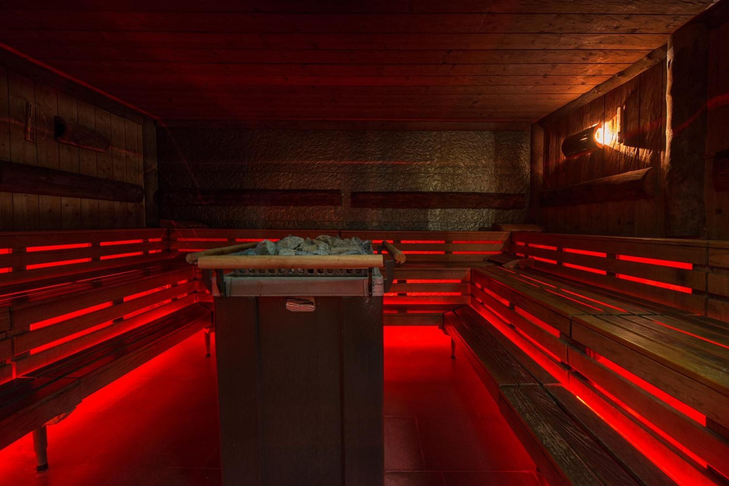 Una habitación tenuemente iluminada con bancos de madera y una mesa de billar.