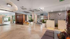 A spacious lobby with a reception desk, seating area, and a decorative wall.