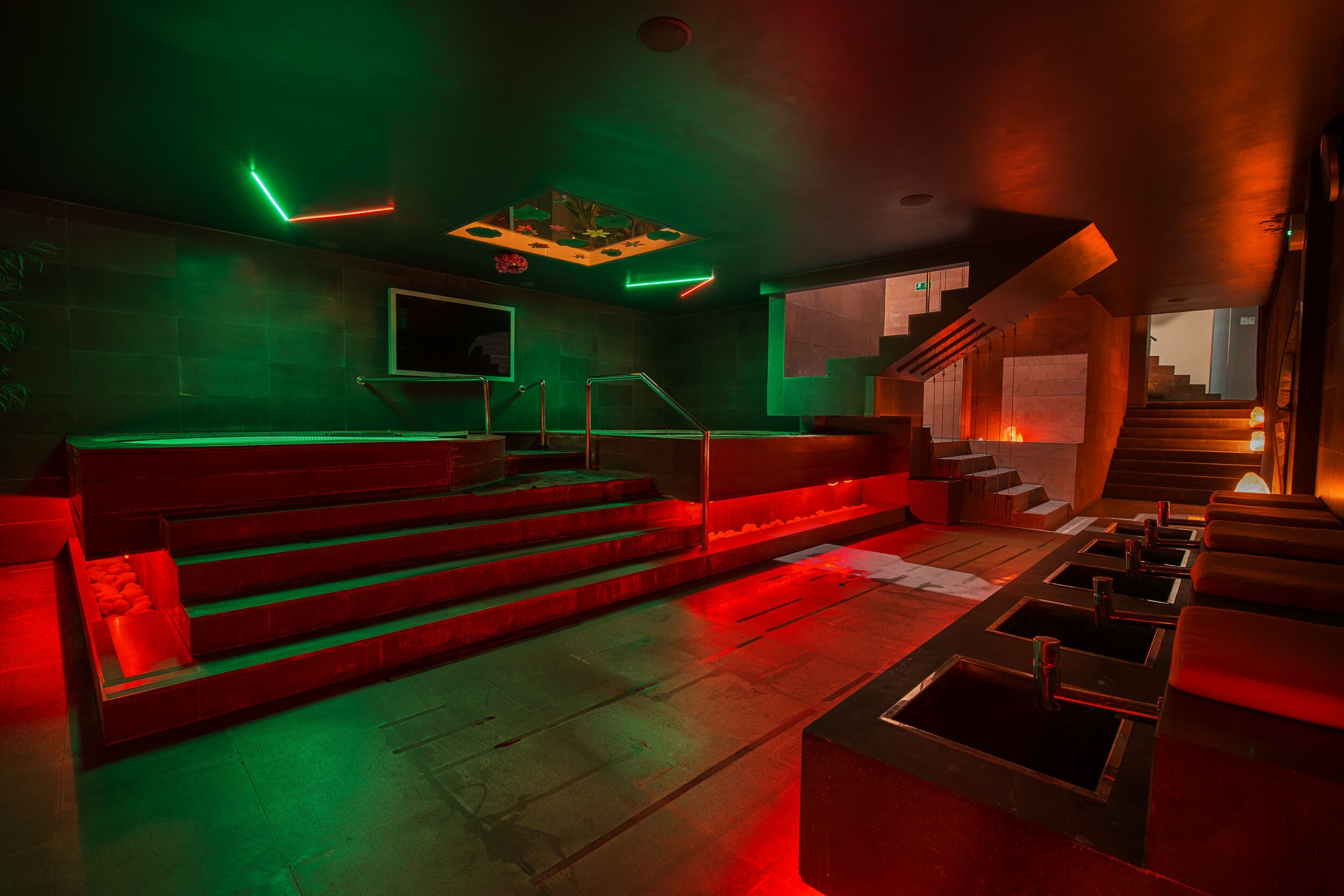 A modern interior with a staircase, seating area, and a neon-lit ceiling.