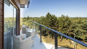 A balcony with wicker furniture and a view of a forested area.
