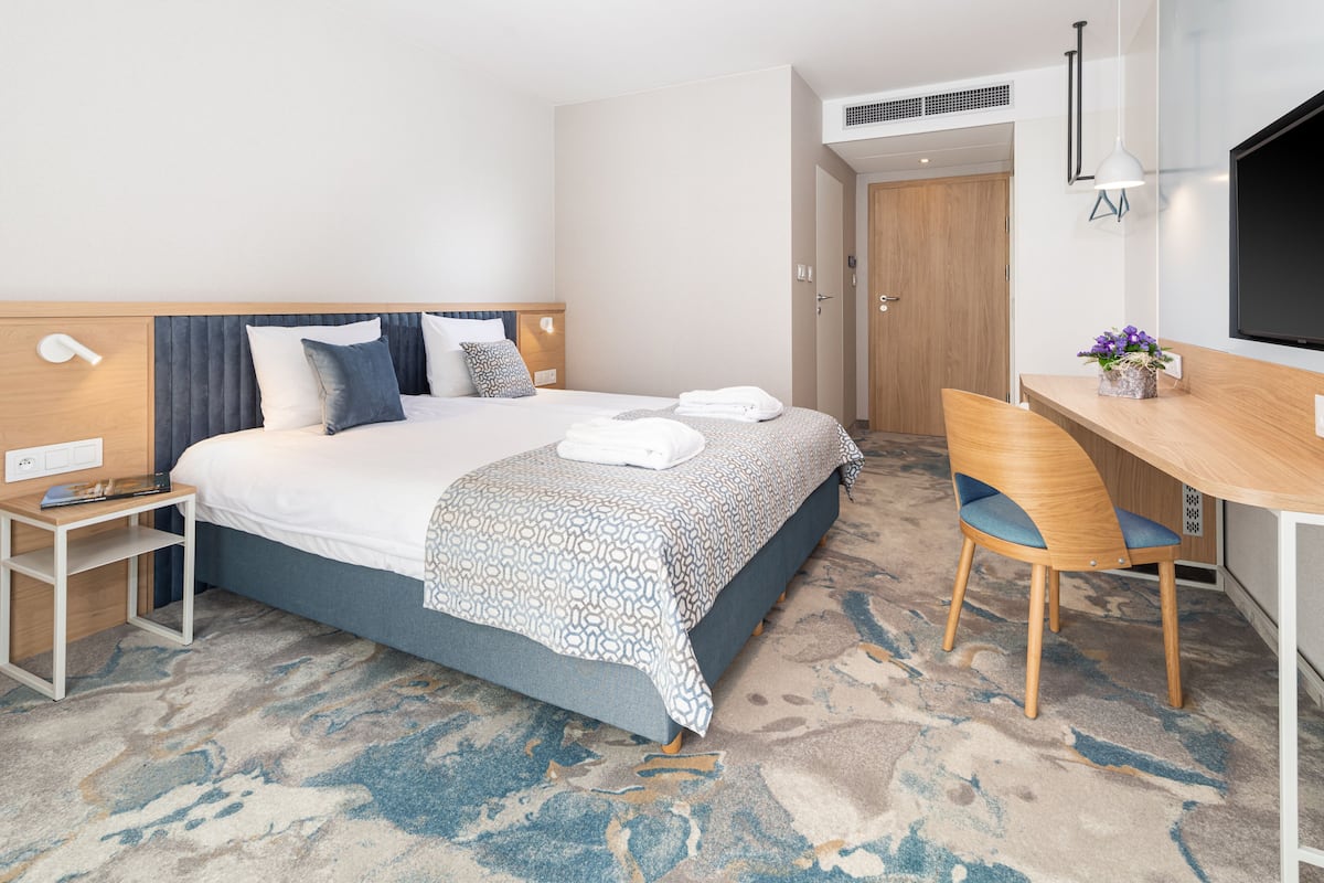 Een hotelkamer met een bed, nachtkastje, stoel, bureau en een televisie.