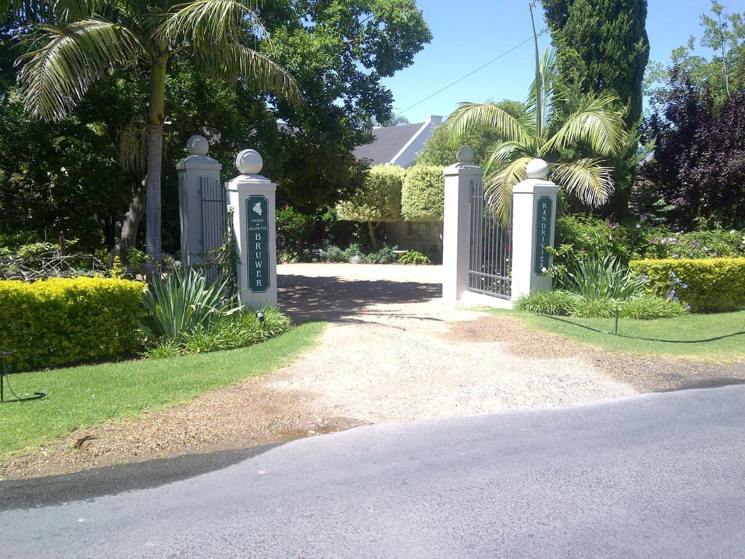 A gated entrance to a property with a gravel driveway leading to a house.