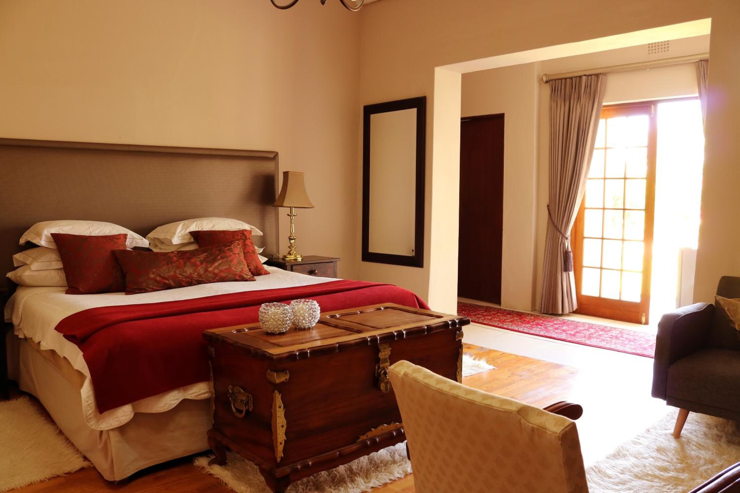 A bedroom with a large bed, a wooden chest, a chair, and a sofa.