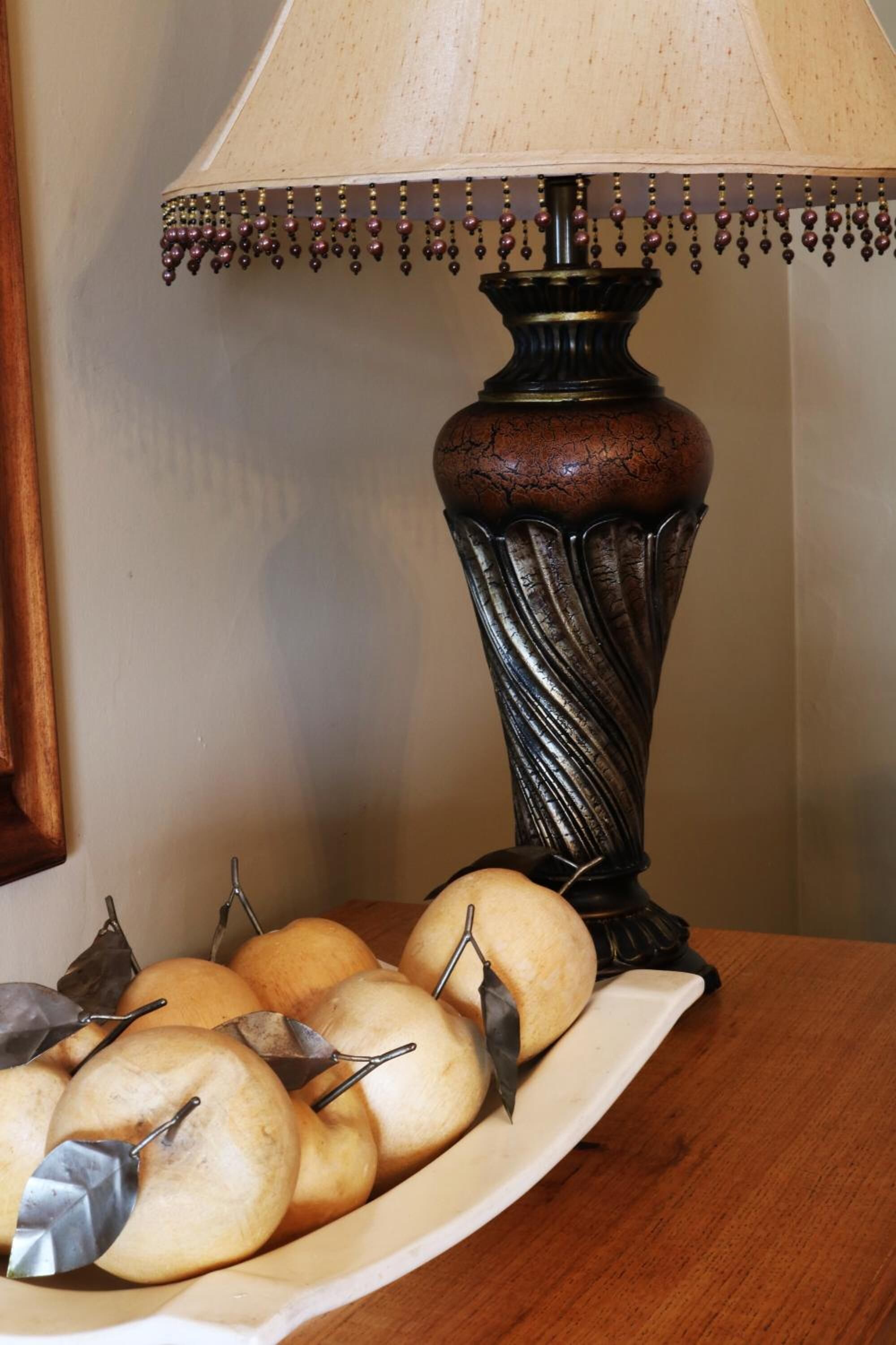 A table with a decorative lamp and a plate of pears.
