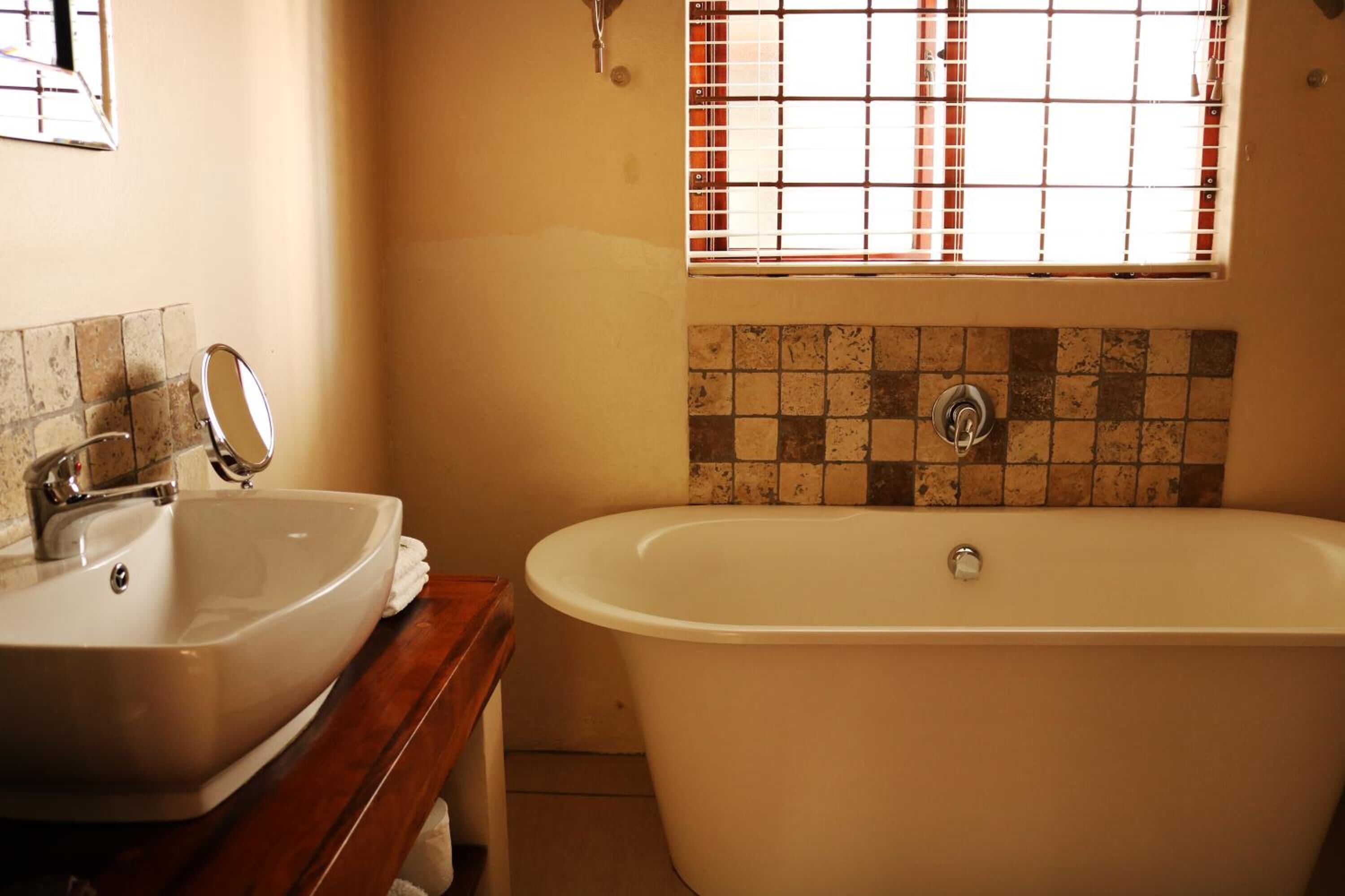 A bathroom with a white sink, a bathtub, and a window with bars.