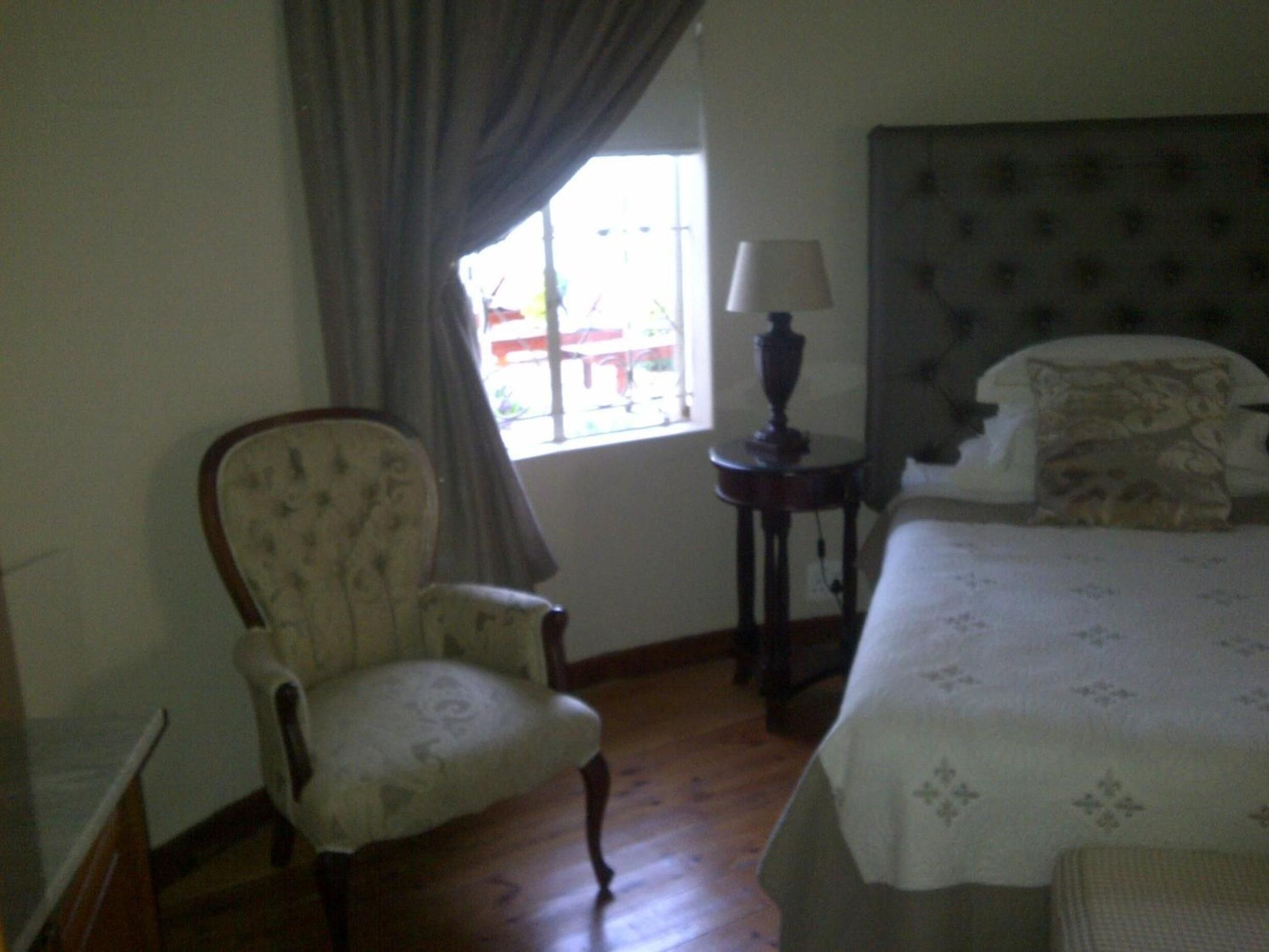 A room with a bed, a chair, a lamp, and a window.