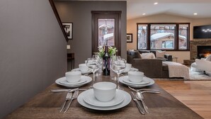 A dining area with a long table set for a meal, a fireplace, and a view of a building outside.