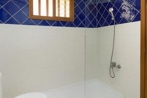A bathroom with a shower, white tiles, and a window with bars. - Home2Book Paradise Costa Adeje, Pool (Playa de las Americas)