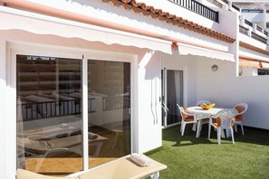 A hotel room with a sliding glass door leading to a balcony with a table and chairs. - Home2Book Paradise Costa Adeje, Pool (Playa de las Americas)