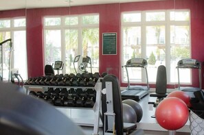 A gym with exercise equipment, treadmills, and dumbbells.