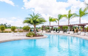 A swimming pool with lounge chairs and palm trees.