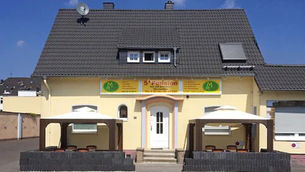 A building with a tiled roof, a sign for '5th Pension', and two covered outdoor seating areas.