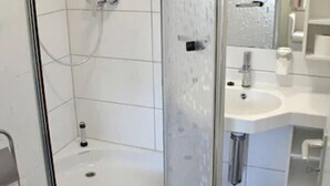 A modern bathroom with a glass-enclosed shower, a white sink, and a mirror.