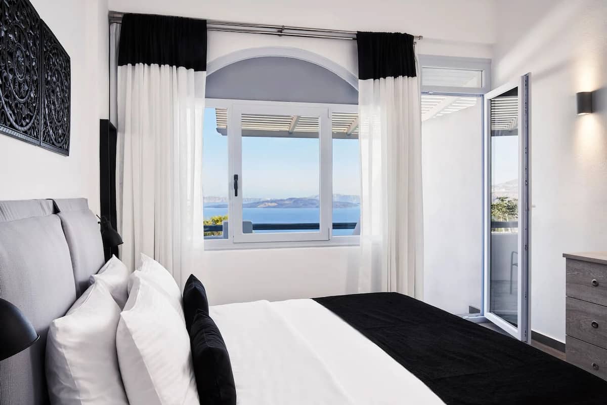 A bedroom with a large bed, a view of the sea, and a sliding door to a balcony.