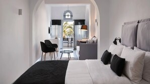Habitación de hotel moderna con una cama grande, un área de estar con una mesa y vistas al exterior a través de un arco.
