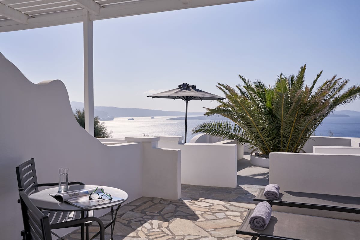 A terrace with a table, chairs, a glass of water, and a towel.