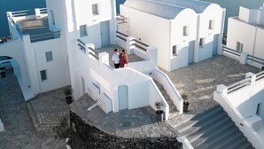 Un edificio blanco con un patio de piedra, una escalera y vistas al mar.