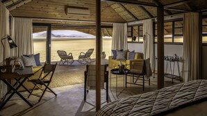 A room with a view of a desert landscape, furnished with a sofa, chairs, and a dining table. -  Kwessi Dunes (Sesriem)