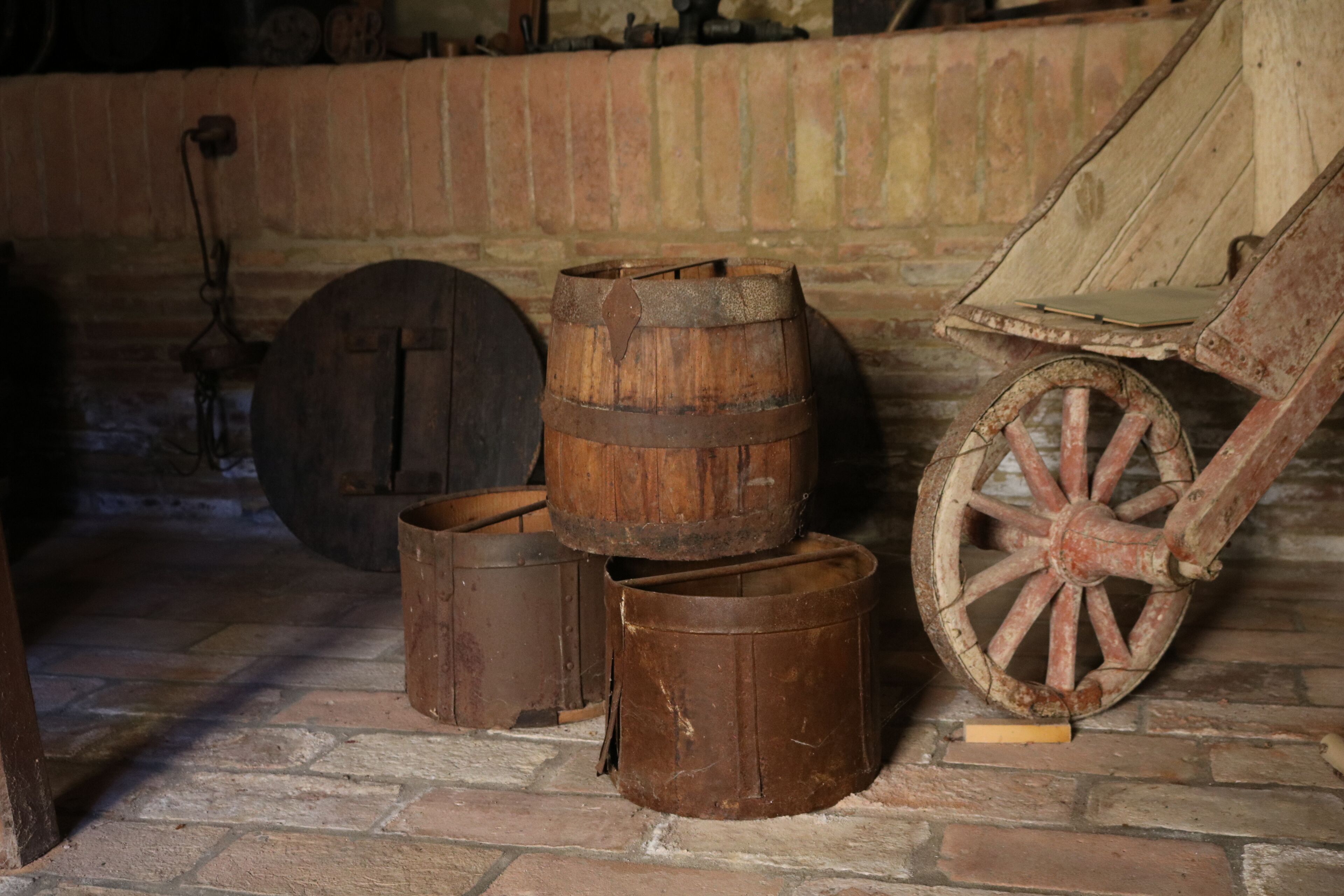 Un interno rustico con botti di legno, una grande ruota e un muro in mattoni.