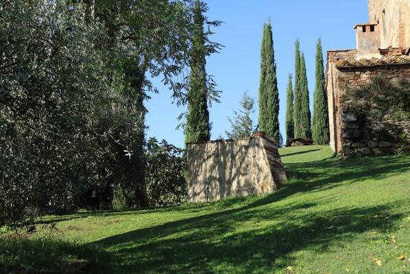 A stone building with a sloped roof, surrounded by a grassy area and tall trees. - Borgo Poneta (Barberino Tavarnelle)