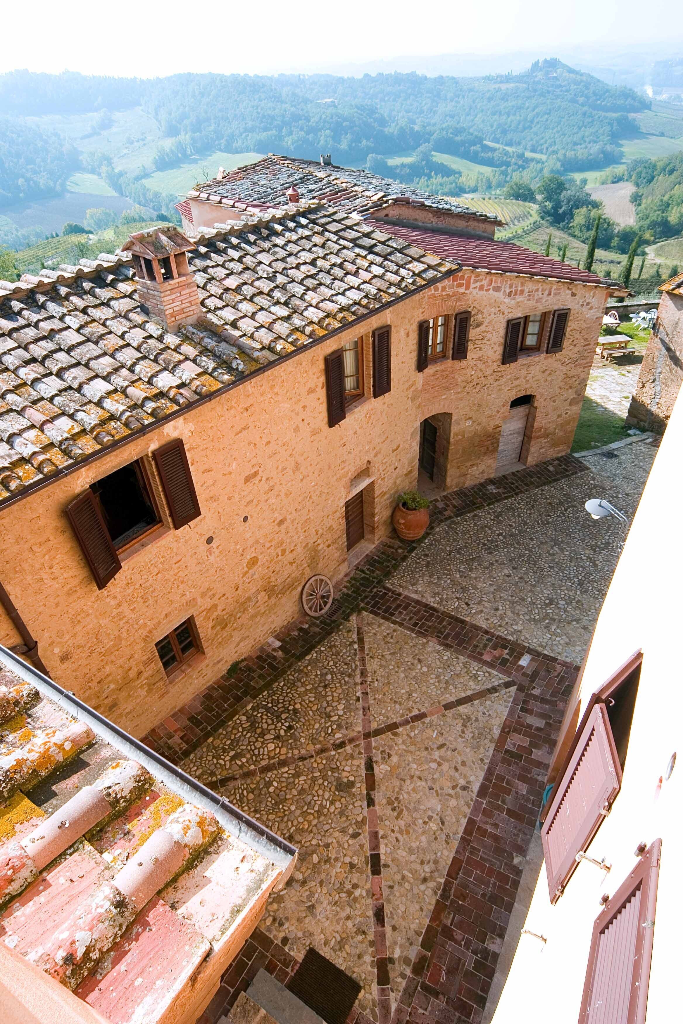 Un edificio de piedra tradicional con un patio, que presenta un tejado de baldosas y un aspecto rústico.