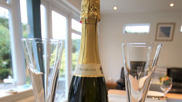Eine Flasche Prosecco, zwei Champagnergläser und eine Schachtel Guylan Pralinen auf einem Tisch.