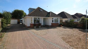 Ein Wohnhaus mit befestigter Auffahrt, Garage und Gartenanlage mit Topfpflanzen.