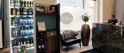 Zona de recepción de hotel con minibar, asientos y un ventanal grande.