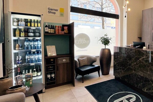 Zona de recepción de hotel con minibar, asientos y un ventanal grande.