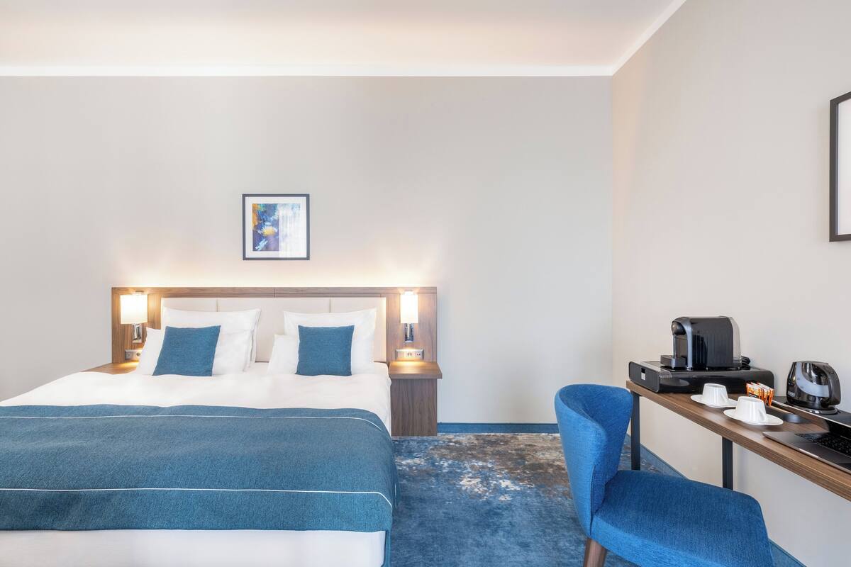 Une chambre d’hôtel avec un lit, un bureau doté d’une machine à café et une chaise.