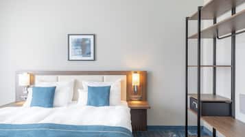 A neatly made bed with a blue bedspread, two pillows, and a headboard with wall-mounted lamps.