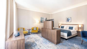 Una habitación de hotel con cama, escritorio, silla, lámpara y obras de arte en las paredes.