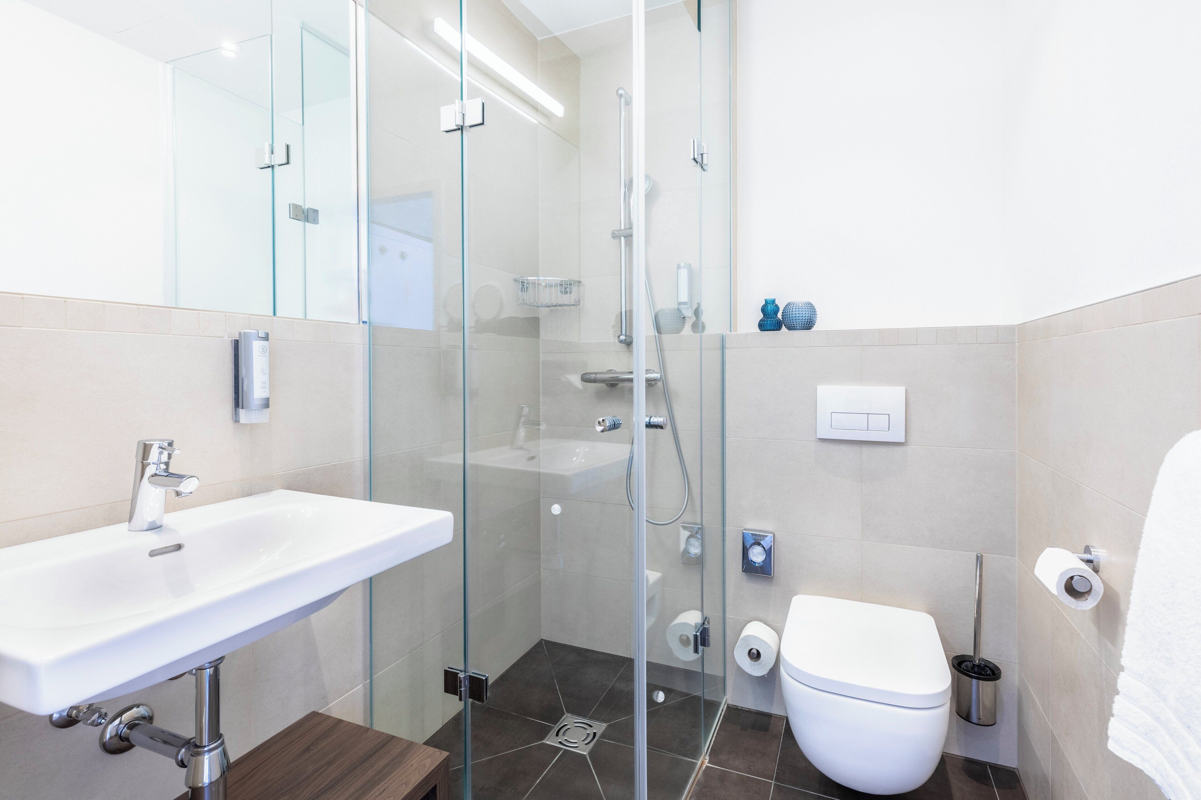 A modern bathroom with a glass-enclosed shower, a white sink, and a toilet.