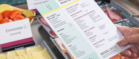 A menu with various food options and a hand holding it.