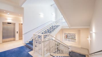 A modern interior with a staircase, elevator, and a blue carpeted area.