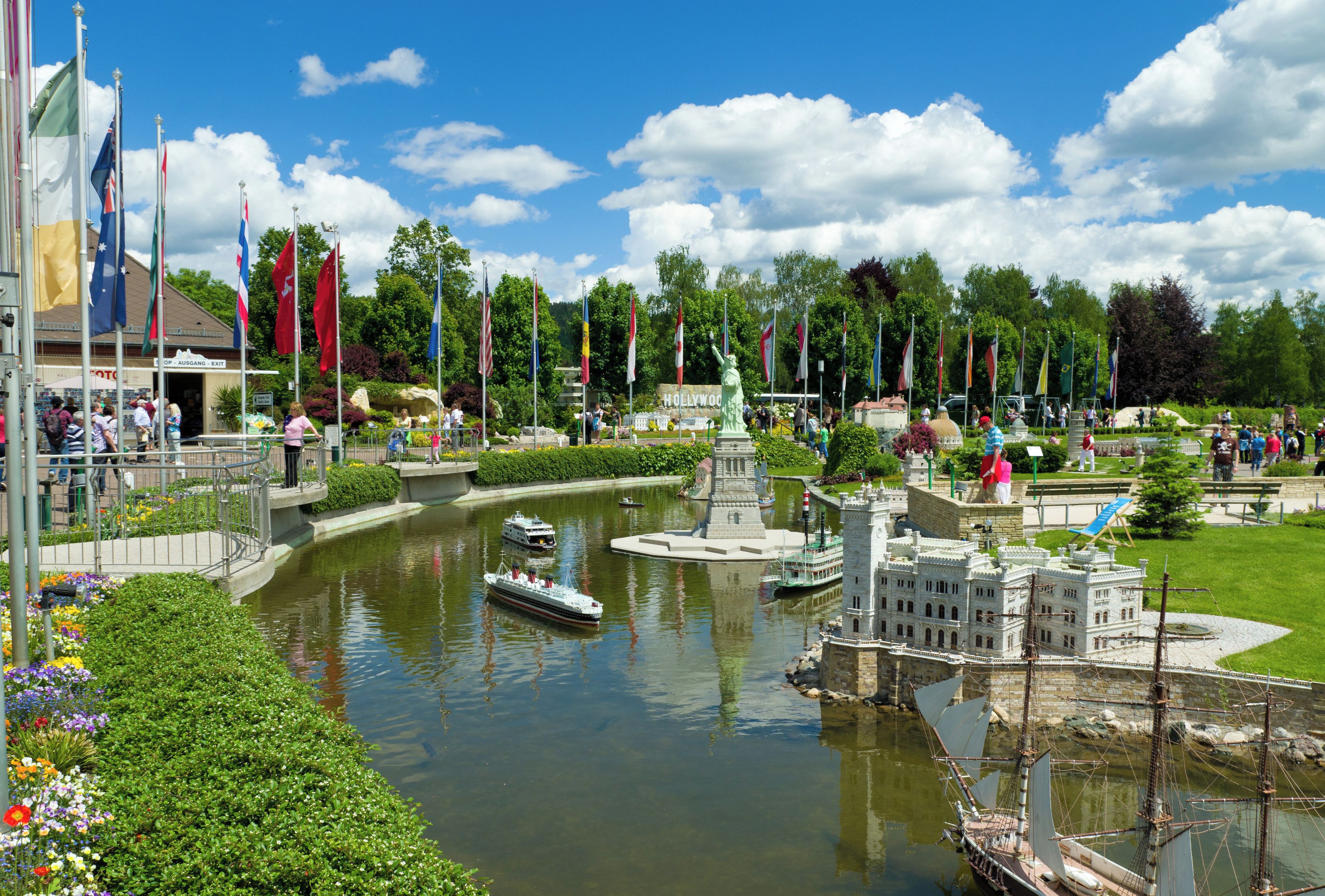 Un parc au bord de la rivière, avec une maquette de navire, une statue et une structure ressemblant à un château.