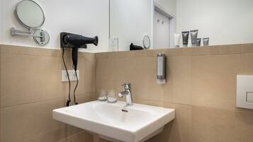 A bathroom with a white sink, a hairdryer, and a mirror.