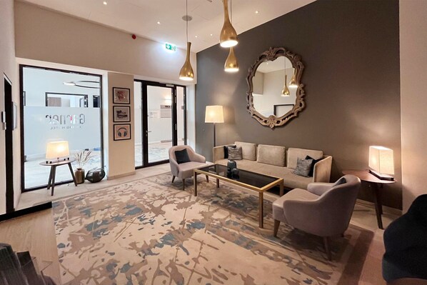 Un moderno vestíbulo de hotel con un sofá, sillones, una mesa de centro y un espejo grande.