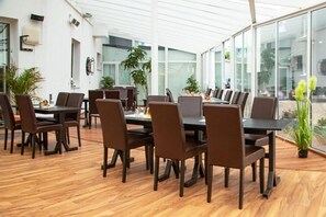 Une salle de conférence moderne dotée d’un plafond en verre, d’un plancher en bois et de chaises marron.