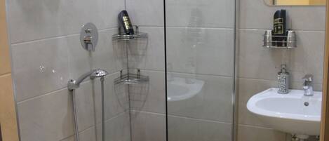 Un baño moderno con ducha de vidrio, inodoro, lavamanos y espejo.